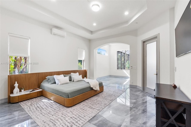 bedroom with multiple windows, a wall mounted air conditioner, and a raised ceiling