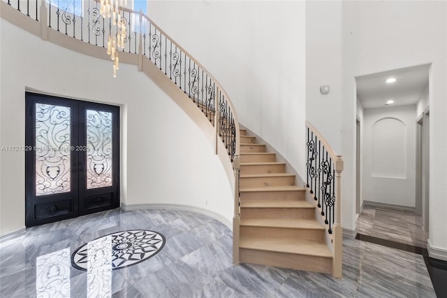 entryway featuring a towering ceiling, a wealth of natural light, and french doors