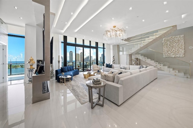 living room with a wealth of natural light, stairs, a chandelier, and a wall of windows