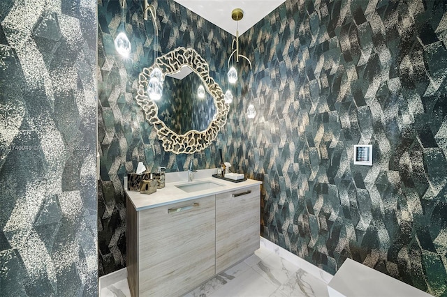 bathroom with marble finish floor, vanity, and wallpapered walls