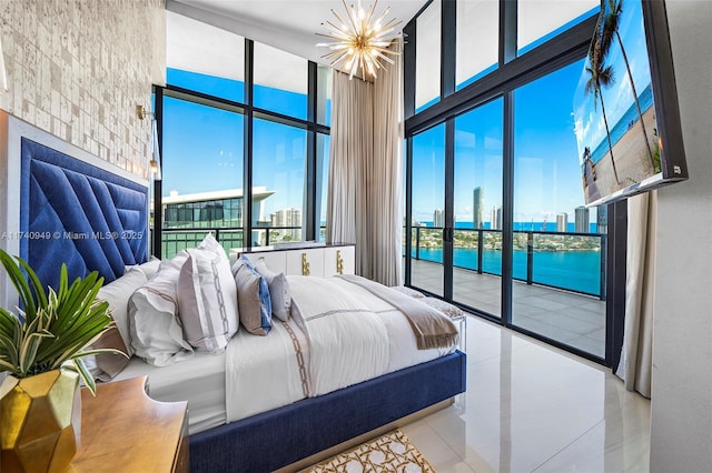 bedroom with a towering ceiling, access to exterior, a chandelier, and a wall of windows