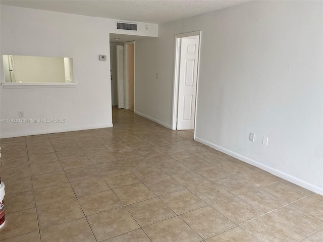 unfurnished room featuring light tile patterned flooring and a textured ceiling