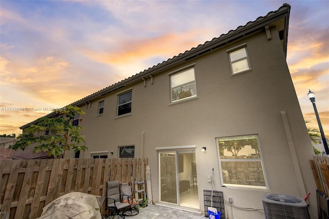 back house at dusk with central AC unit and a patio area