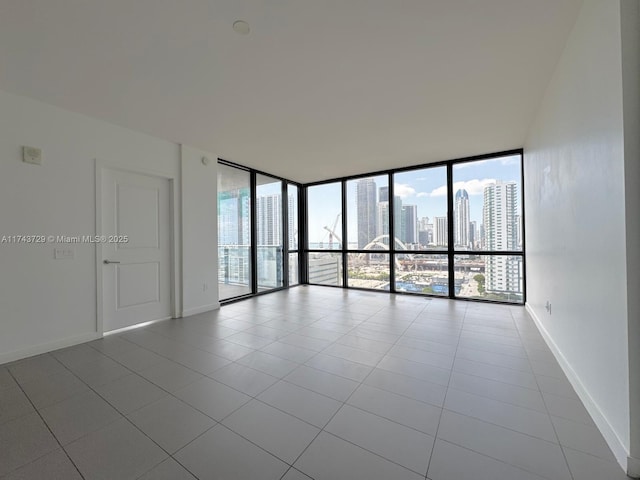 tiled empty room with baseboards, a view of city, and plenty of natural light