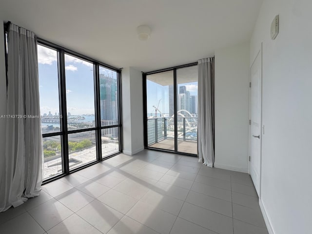 tiled empty room with a view of city, baseboards, and a wall of windows
