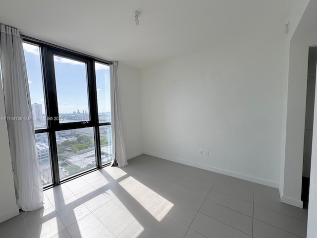 unfurnished room with baseboards, a wealth of natural light, and light tile patterned flooring