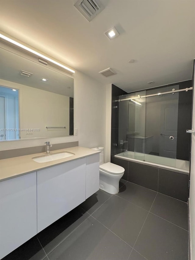 bathroom with visible vents, tiled shower / bath combo, toilet, vanity, and tile patterned flooring