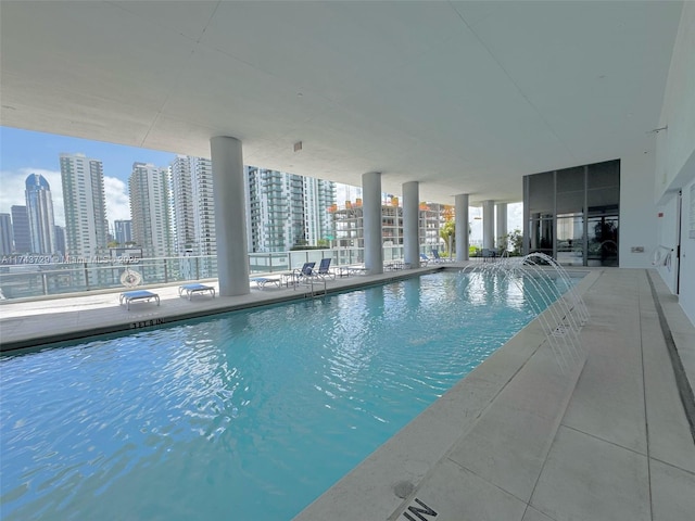 community pool with a view of city, fence, and a patio area