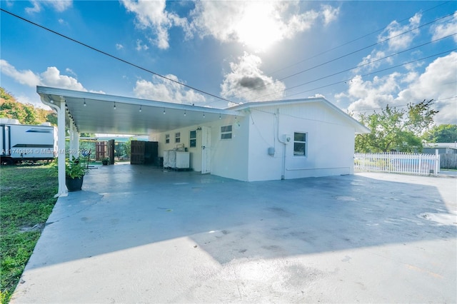 view of property exterior with a carport, fence, and driveway