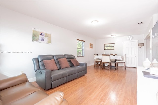 living area with baseboards, visible vents, and wood finished floors