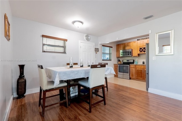 dining space featuring light wood-style floors, baseboards, and visible vents