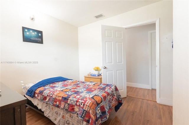 bedroom with wood finished floors, visible vents, and baseboards