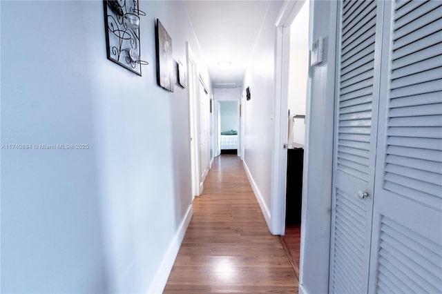 corridor featuring wood finished floors and baseboards