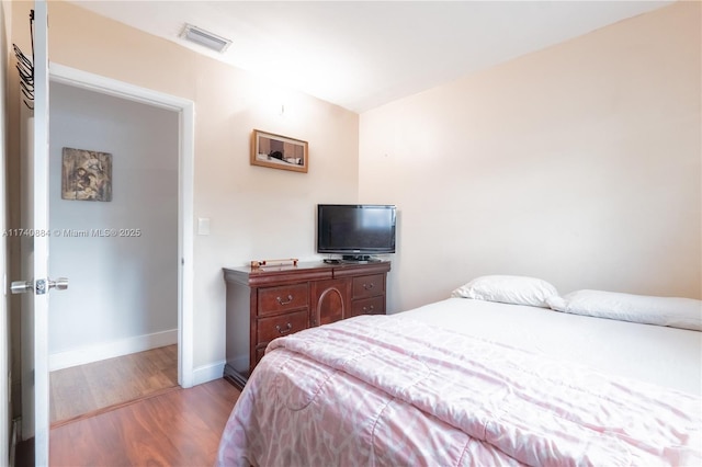 bedroom featuring light wood-type flooring, visible vents, and baseboards