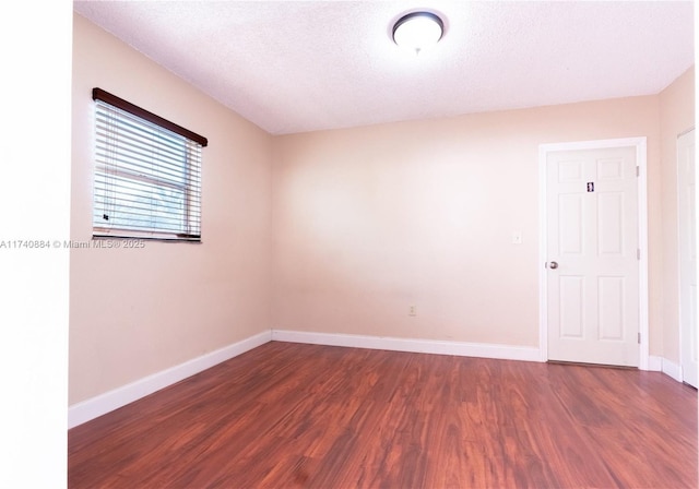 empty room featuring baseboards, dark wood finished floors, and a textured ceiling