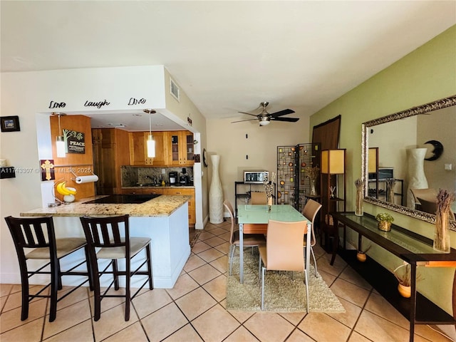 kitchen featuring brown cabinets, light tile patterned floors, tasteful backsplash, visible vents, and a peninsula