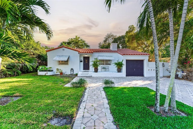 mediterranean / spanish-style house with a garage and a lawn