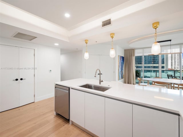 kitchen featuring white cabinetry, stainless steel dishwasher, decorative light fixtures, and sink