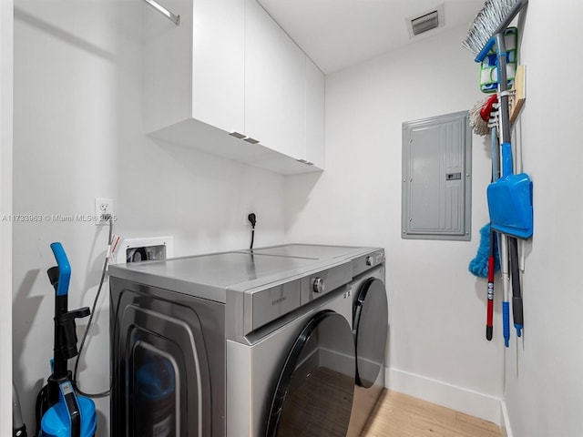 laundry room with washer and dryer, light hardwood / wood-style floors, electric panel, and cabinets