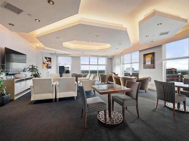 carpeted dining area with a raised ceiling