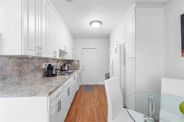 kitchen featuring sink, light hardwood / wood-style flooring, white fridge, white cabinets, and backsplash