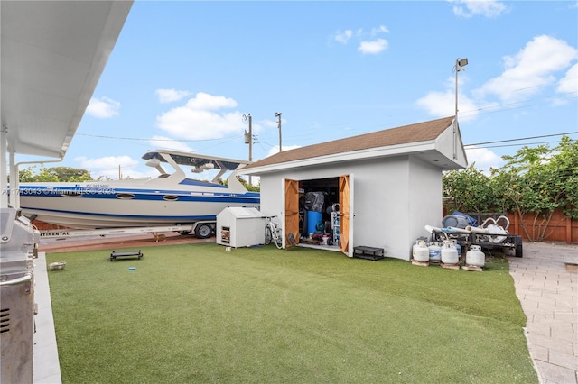 view of yard with fence, a storage unit, and an outbuilding