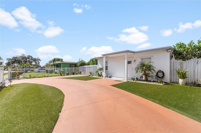view of front of house featuring a front yard, stucco siding, driveway, and fence