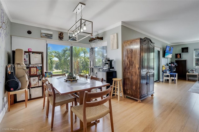 dining space with a notable chandelier, crown molding, and light wood-type flooring