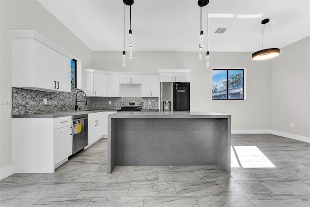 kitchen featuring sink, decorative light fixtures, a center island, appliances with stainless steel finishes, and white cabinets