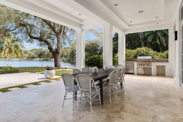 view of patio with area for grilling, an outdoor kitchen, and a water view