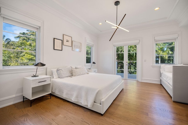 bedroom featuring ornamental molding, light wood-type flooring, multiple windows, and access to outside