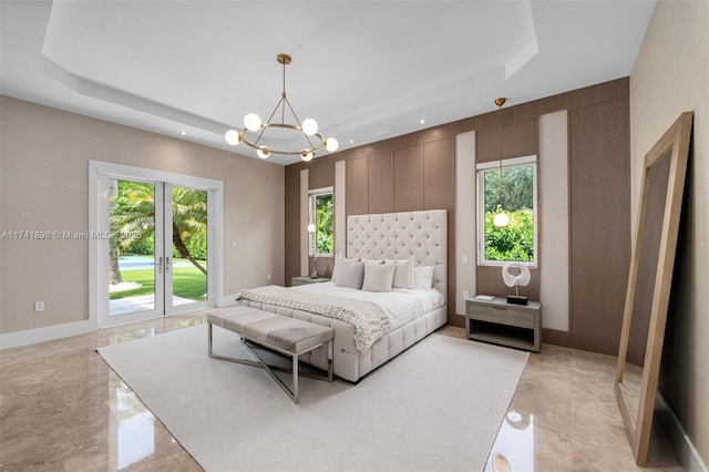 bedroom featuring french doors, a tray ceiling, a chandelier, and multiple windows