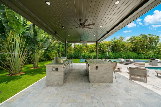 view of patio with an outdoor kitchen, area for grilling, an outdoor bar, and ceiling fan