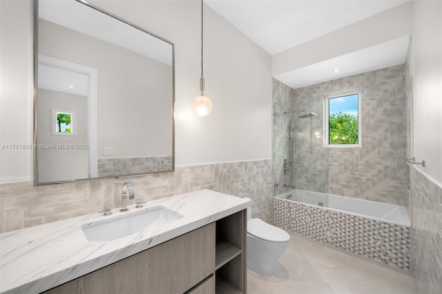 full bathroom featuring tiled shower / bath, tile walls, tile patterned flooring, vanity, and toilet