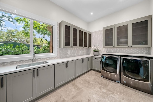 washroom with cabinets, washer and dryer, and sink