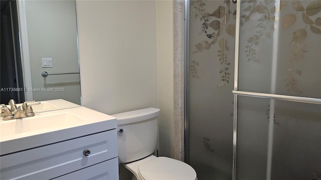 bathroom featuring vanity, a shower with shower door, and toilet