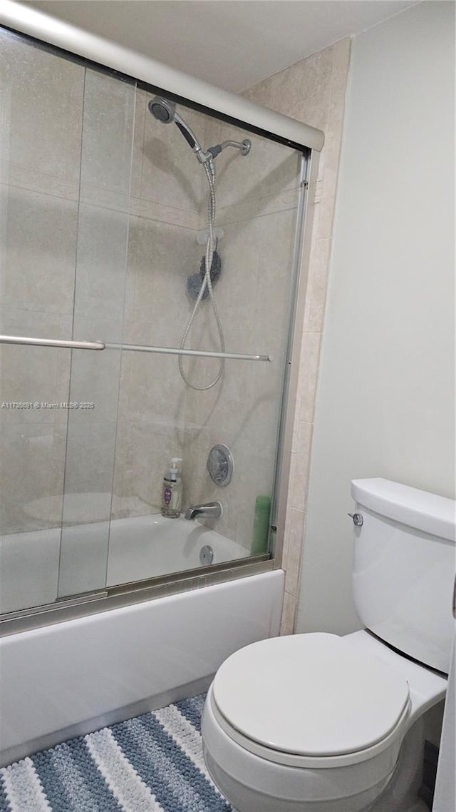 bathroom with tile patterned flooring, enclosed tub / shower combo, and toilet