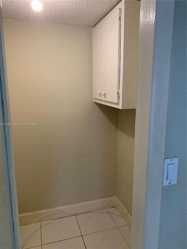 clothes washing area with light tile patterned floors and a textured ceiling