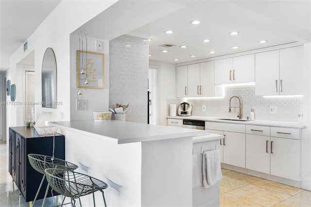 kitchen featuring sink, white cabinets, backsplash, and kitchen peninsula