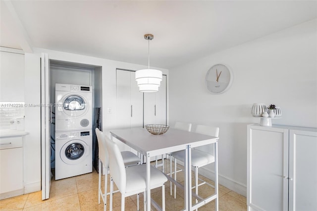 tiled dining room featuring stacked washer / dryer