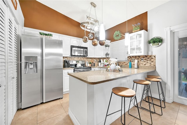 kitchen featuring appliances with stainless steel finishes, decorative light fixtures, white cabinetry, a breakfast bar area, and kitchen peninsula