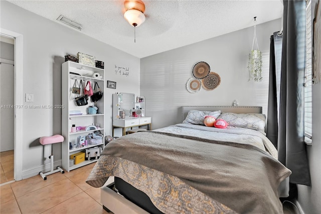 bedroom featuring light tile patterned flooring, vaulted ceiling, ceiling fan, and a textured ceiling