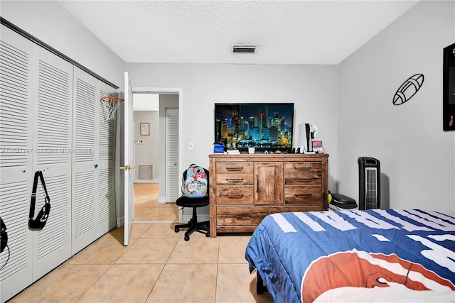 tiled bedroom with a closet and a textured ceiling