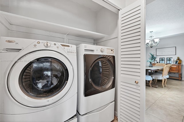 washroom with light tile patterned flooring, independent washer and dryer, a textured ceiling, and a notable chandelier