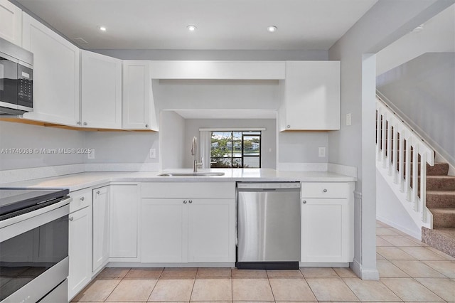 kitchen with light tile patterned floors, stainless steel appliances, a sink, white cabinetry, and light countertops