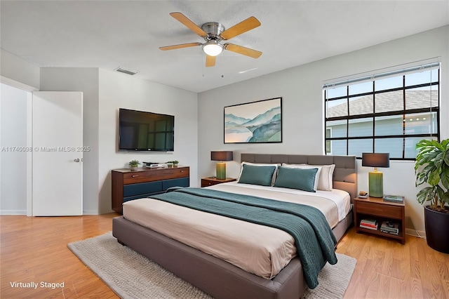 bedroom featuring baseboards, visible vents, ceiling fan, and light wood finished floors