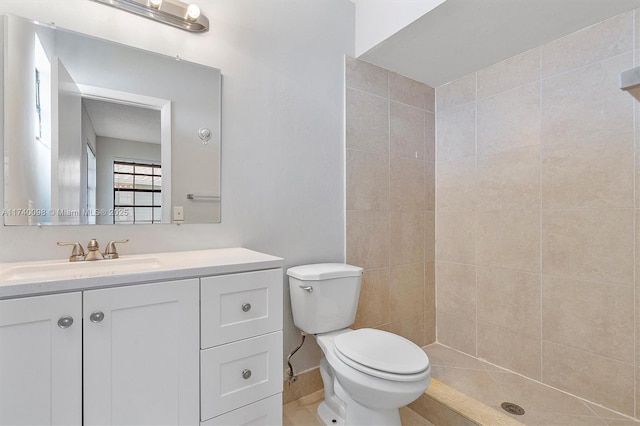 full bathroom featuring a tile shower, vanity, and toilet