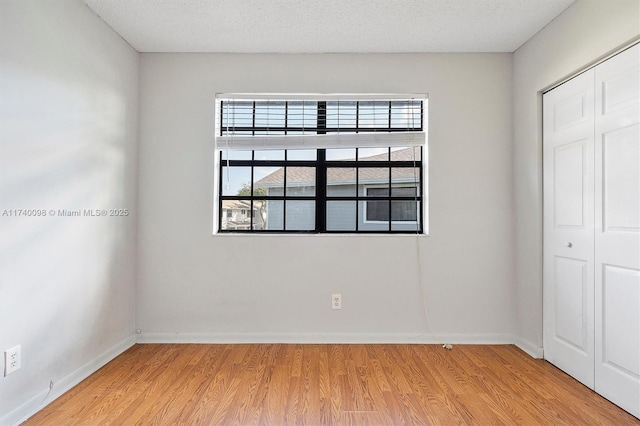 spare room with light wood-type flooring, plenty of natural light, and baseboards