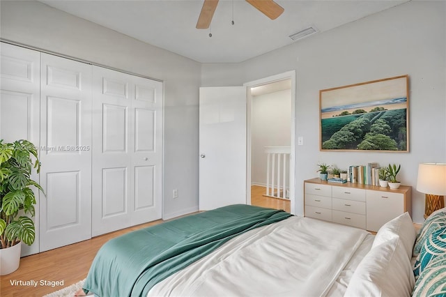 bedroom featuring light wood-type flooring, ceiling fan, visible vents, and a closet