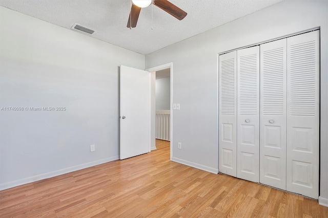 unfurnished bedroom with light wood finished floors, a closet, visible vents, a textured ceiling, and baseboards